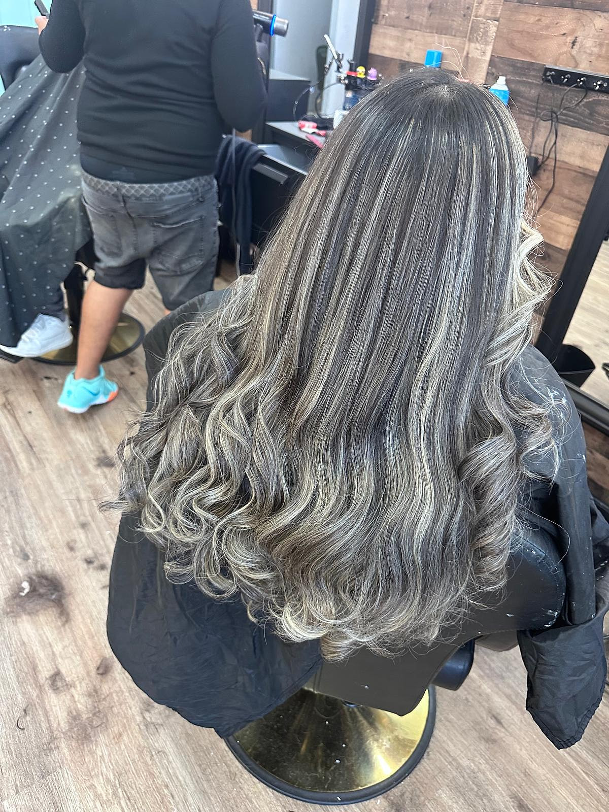 Cabello largo con mechas plateadas y ceniza difuminadas sobre base castaña, alisado con puntas rizadas — trabajo de Miriam Fuerte.