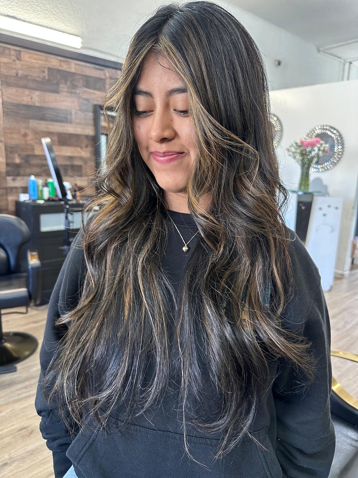 Cabello largo oscuro con balayage caramelo cálido, en ondas suaves.