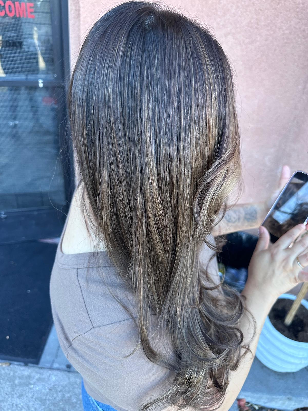 Balayage bronde suave en cabello largo con degradado natural, al aire libre.