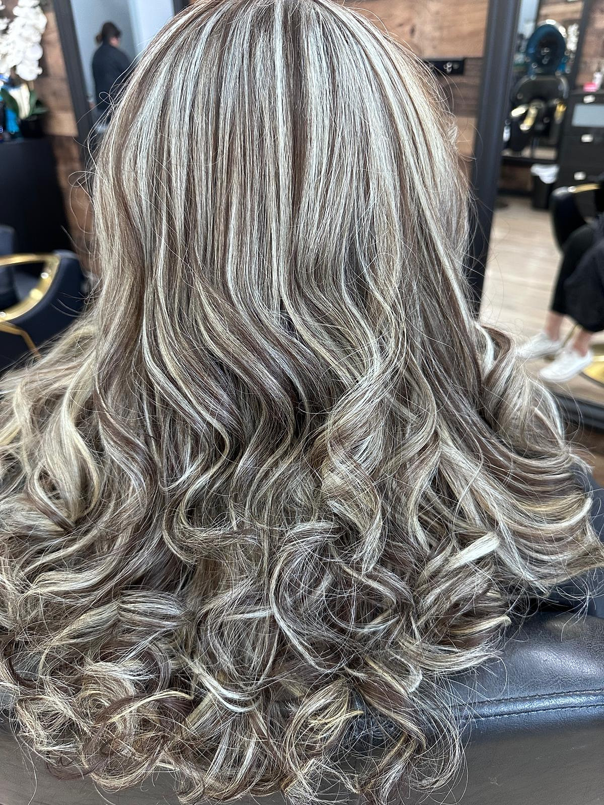 Cabello largo con mechas plateadas intensas sobre castaño, en rizos con volumen.