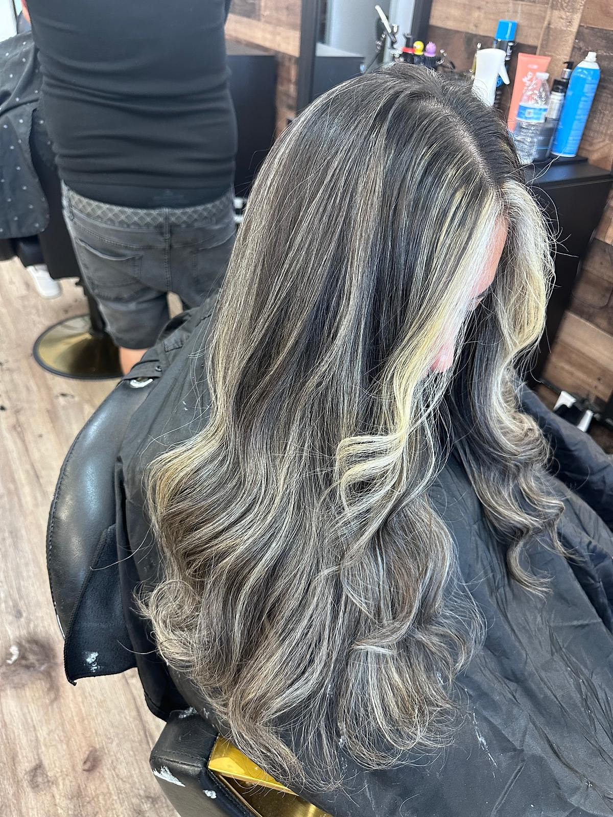 Cabello oscuro con money-piece brillante y mechas con dimensión, en ondas.