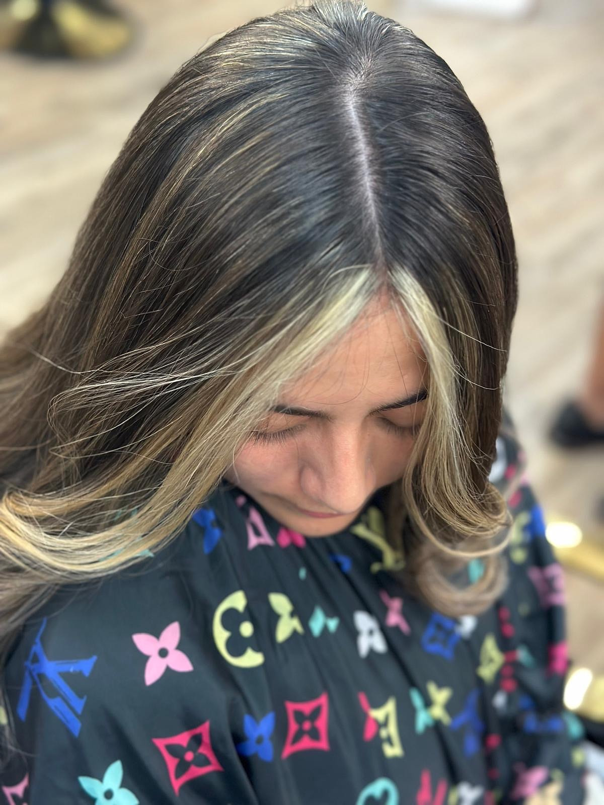 Vista superior de cabello oscuro con mechas rubias que enmarcan el rostro.