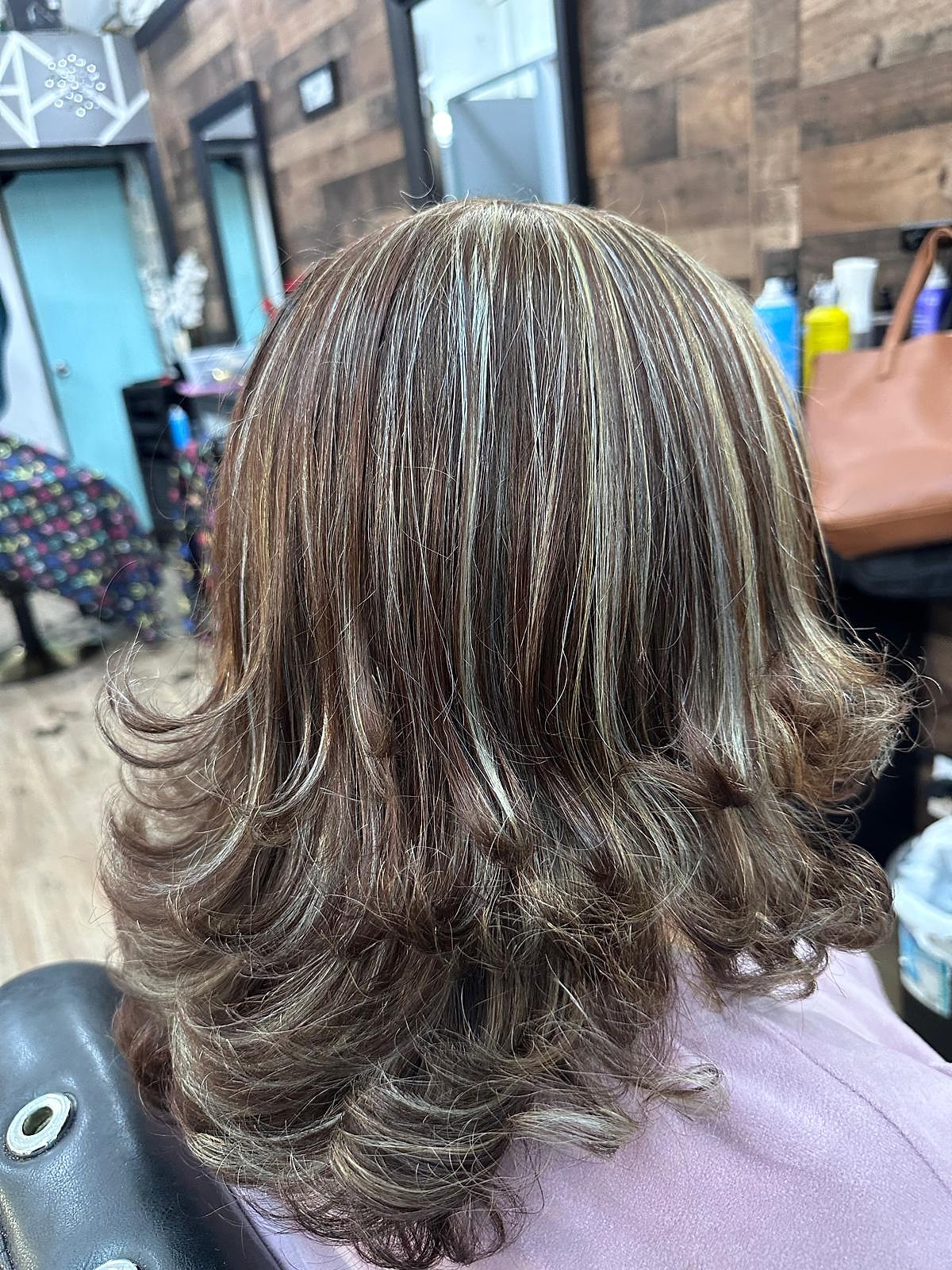 Cabello a los hombros con mechas plateadas y secado redondeado con volumen.