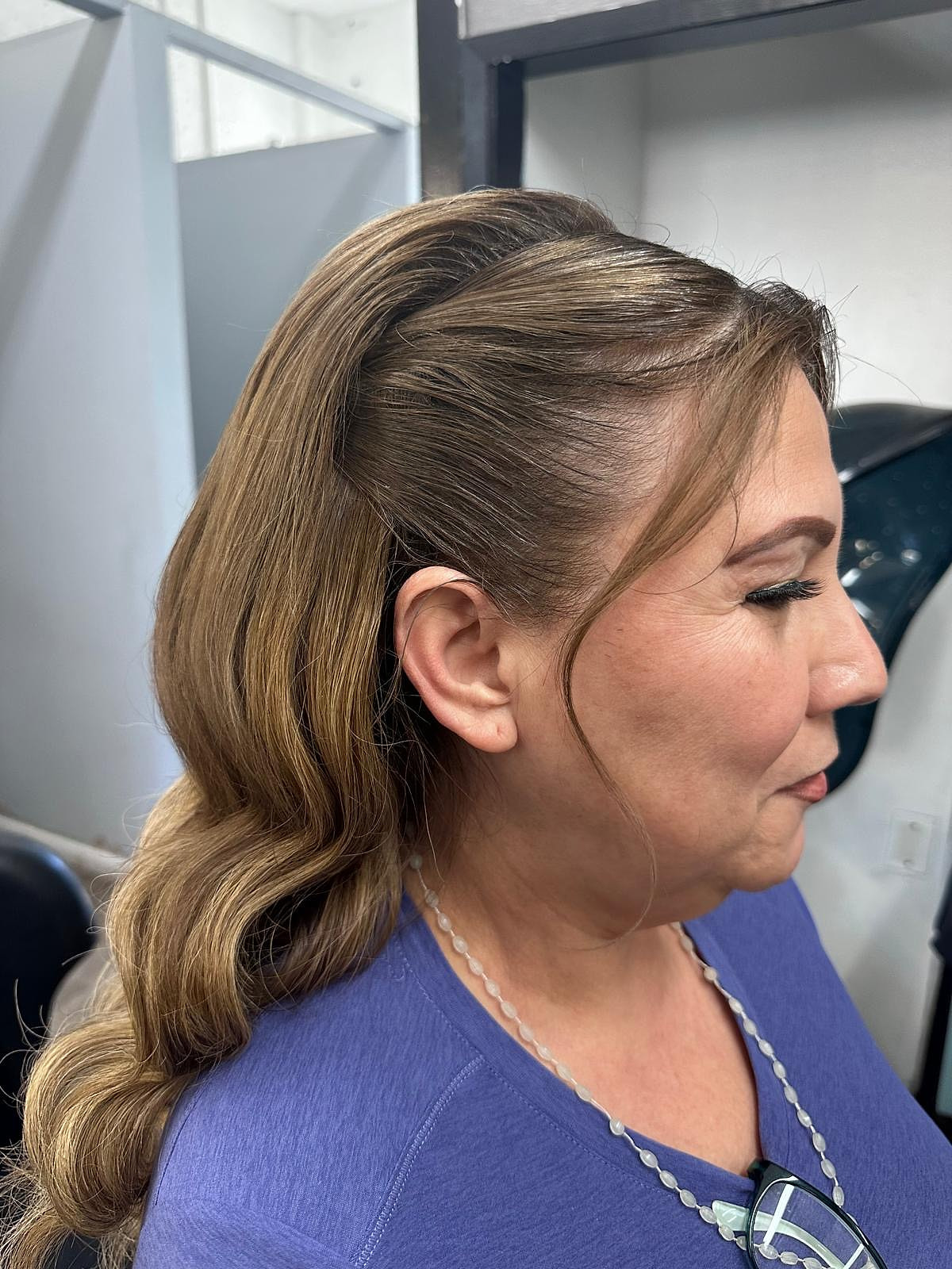Perfil de un recogido suave con ondas, con maquillaje y pestañas.