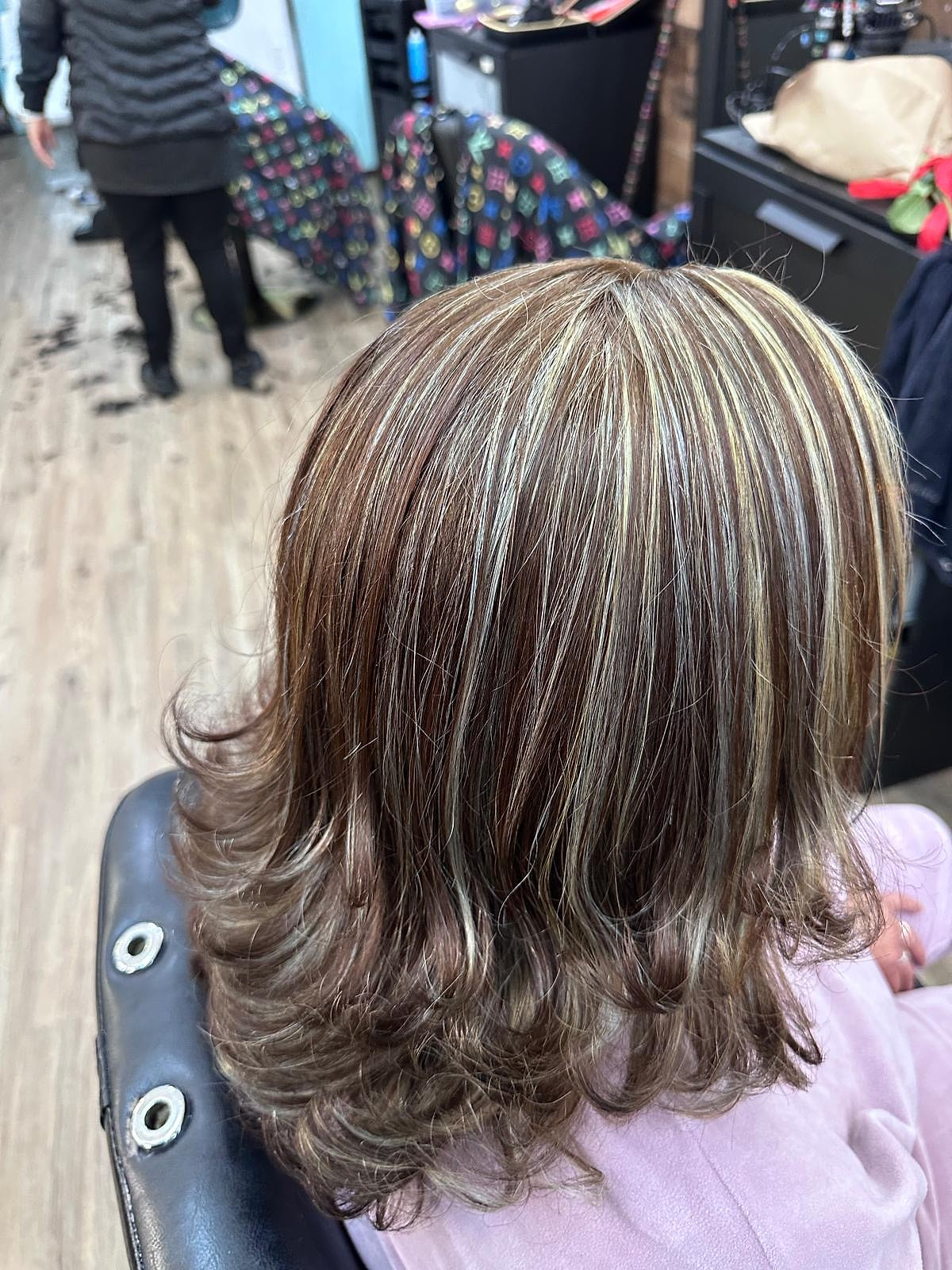 Cabello media melena en capas con mechas plateadas marcadas y puntas hacia afuera.
